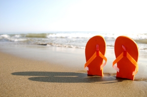 A pair of orange flip flops stuck into a beach